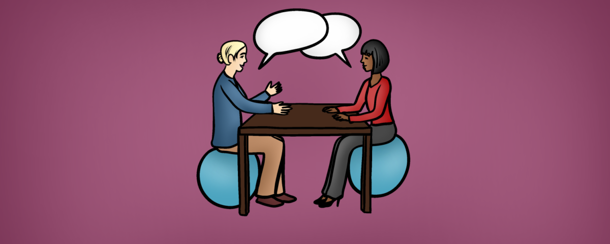 Two individuals sitting at a table and talking
